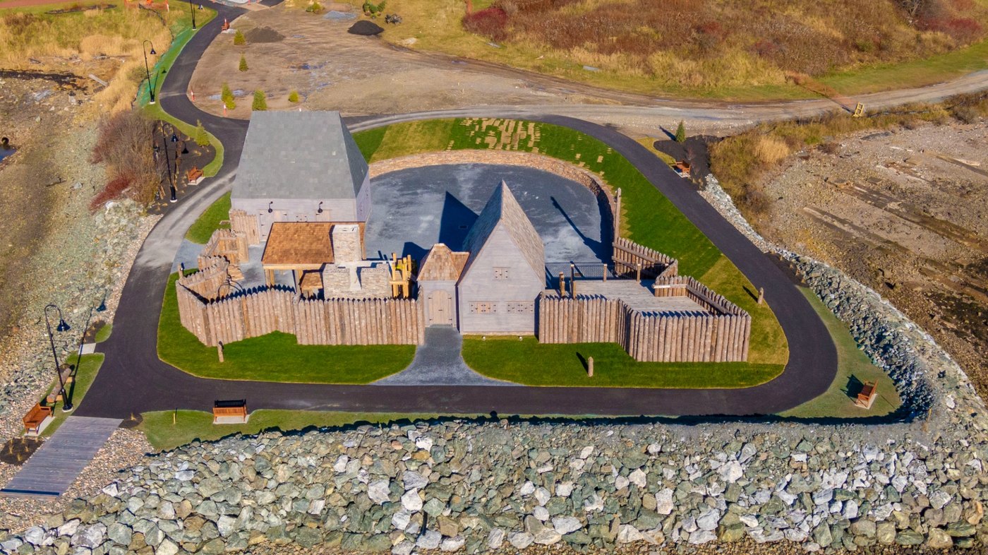 Close aerial of the reconstructed fort showing the timber palisade, buildings, and towers