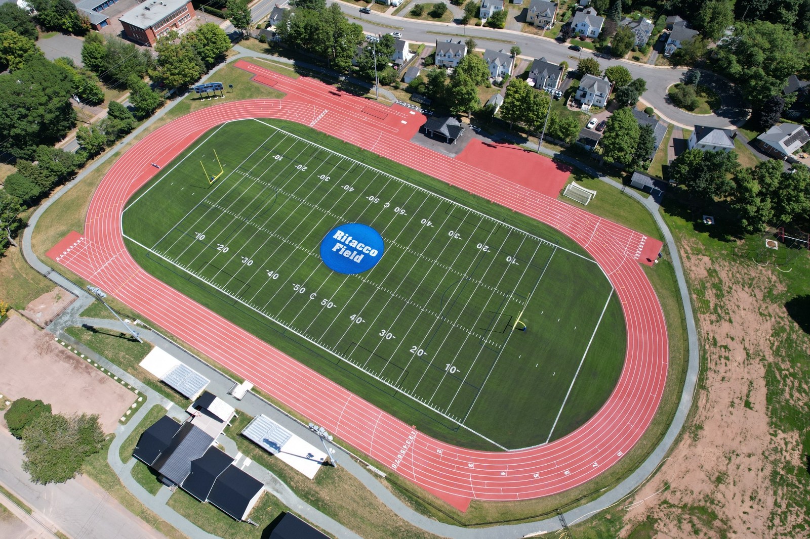 Daytime aerial of the completed athletic park showing the red track ringing the synthetic turf field